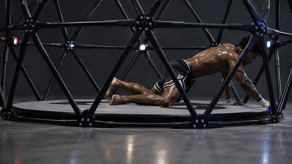 A combat-sport athlete moving through a footwork task inside CogniCage.