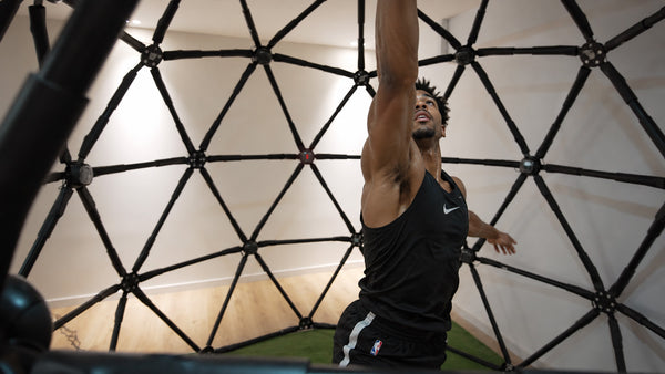 A court-sport athlete changing direction toward a cue inside CogniCage.