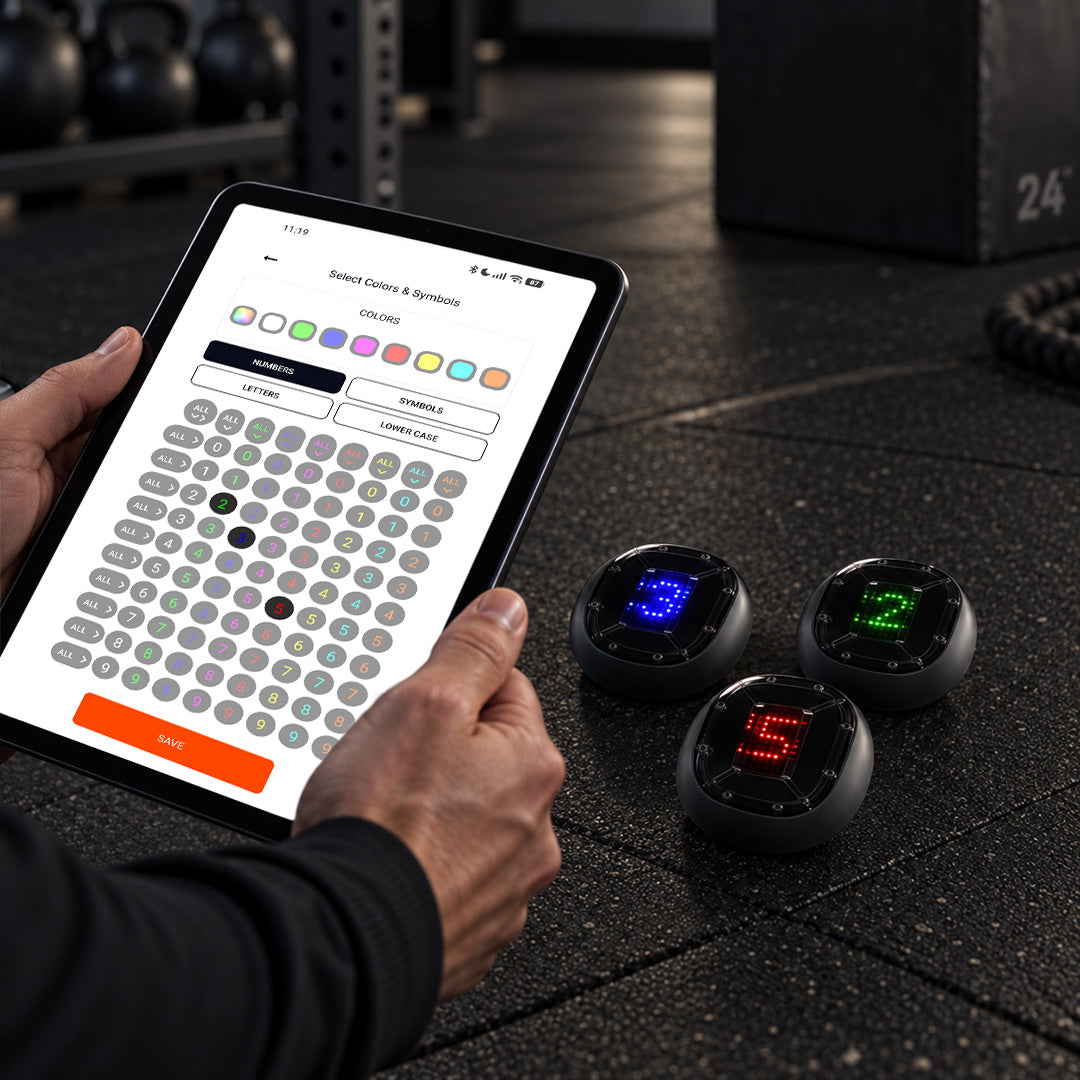 A coach controlling a CogniCage session from a tablet while an athlete trains inside the environment.